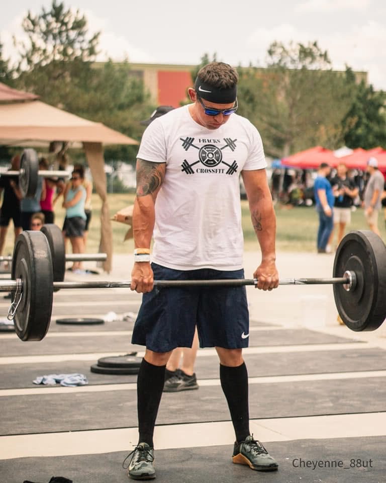 Ty McMillan setting up for a barbell deadlift at an outdoor fitness event