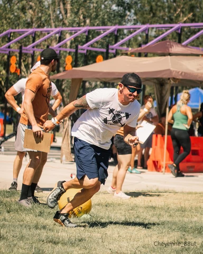 Ty McMillan running with a ball across the grass at an outdoor fitness event