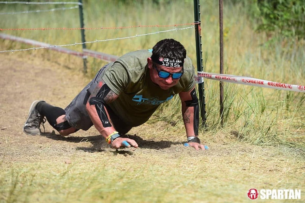 Ty McMillan crawling under barbed wire at a Spartan race